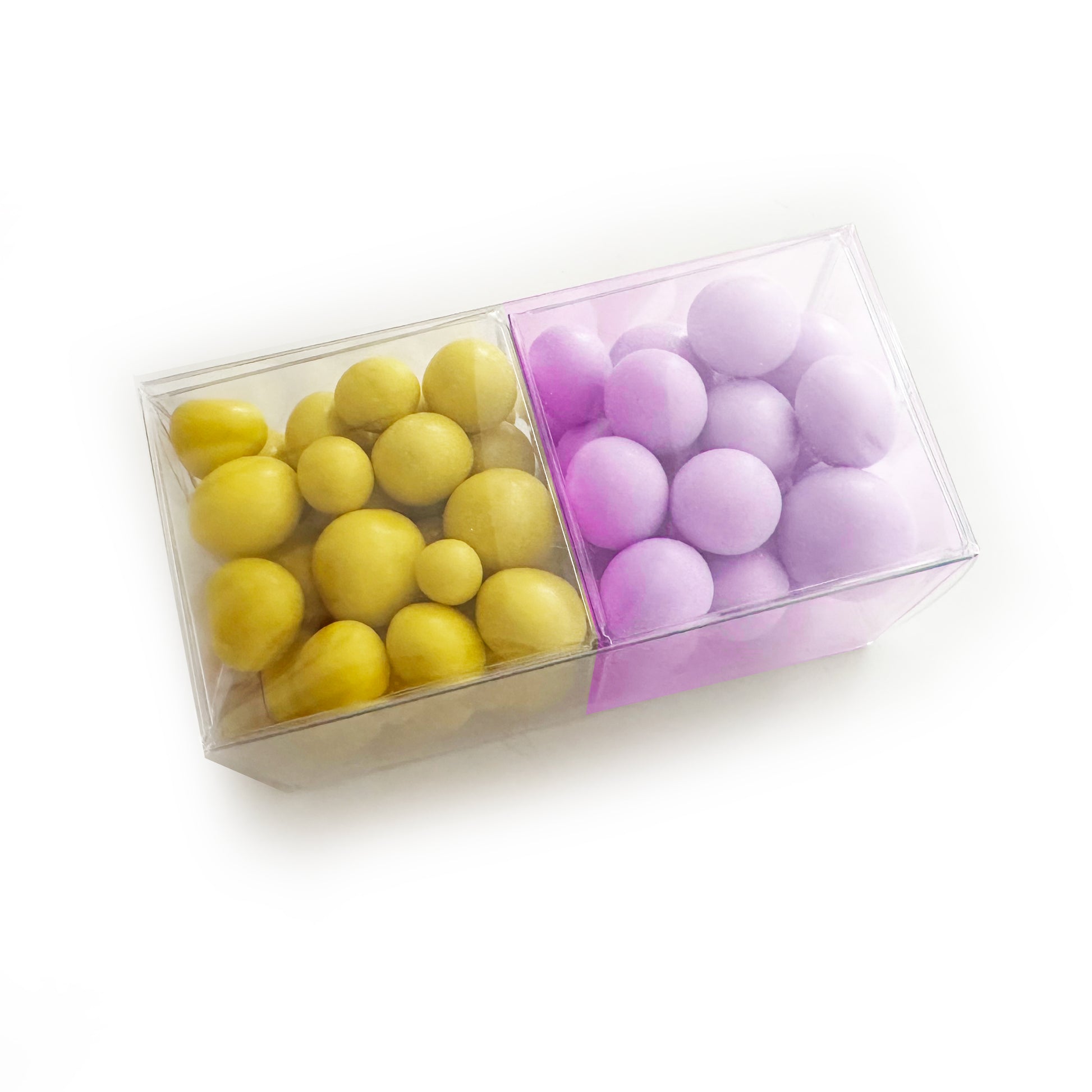 Clear box with yellow and purple spherical candies on a white background